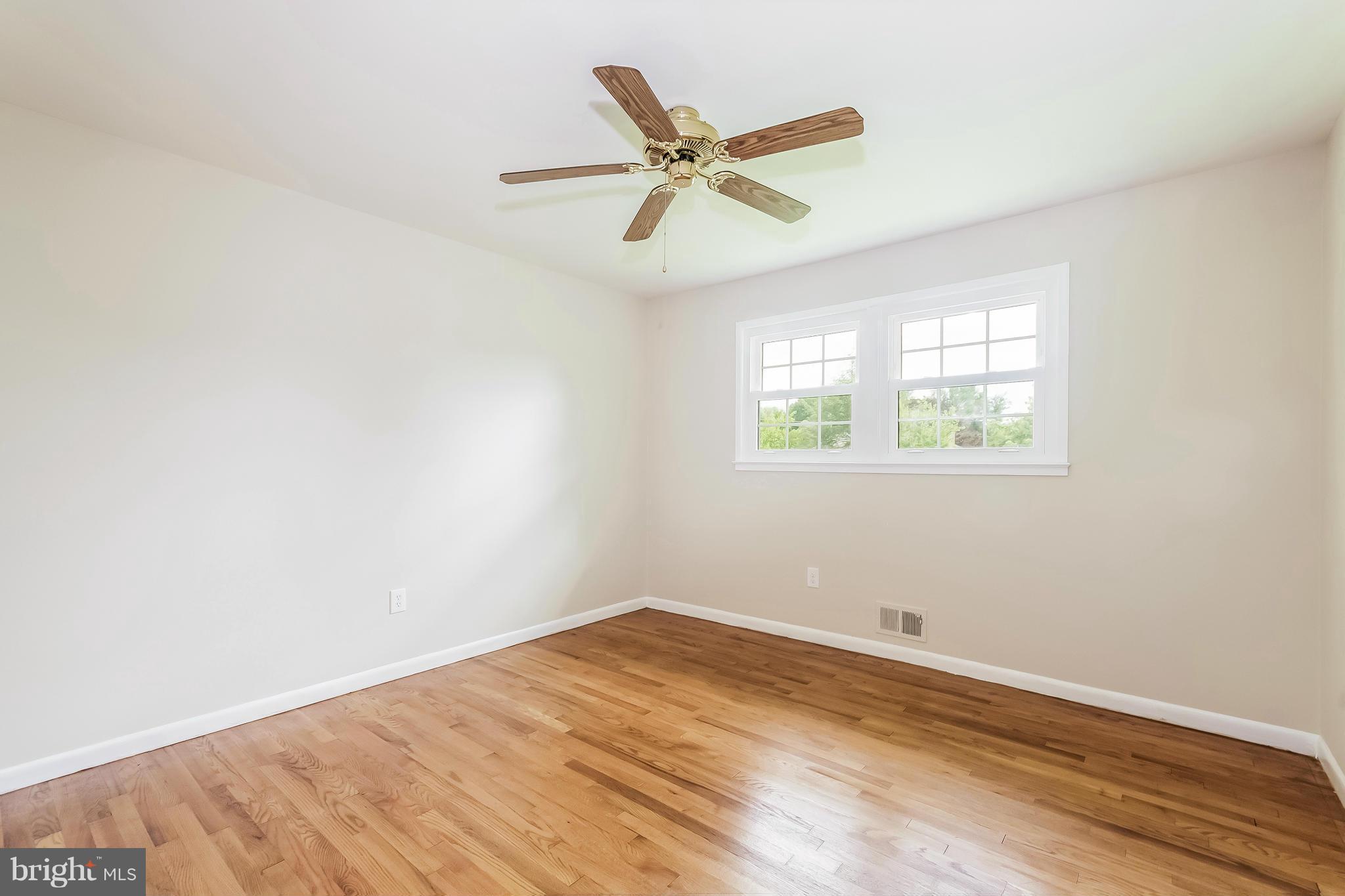 14517 Cobblestone Drive Silver Spring, MD 20905 - Photo 15 of 30 an empty room with wooden floor ceiling fan and windows