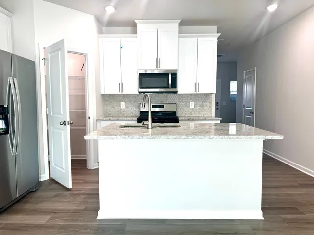 a kitchen with stainless steel appliances granite countertop a refrigerator a stove and a sink