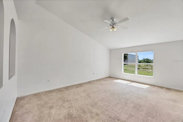 an empty room with chandelier fan and windows