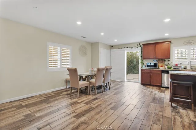 a kitchen with stainless steel appliances granite countertop a stove a sink a refrigerator with a dining table and chairs with wooden floor