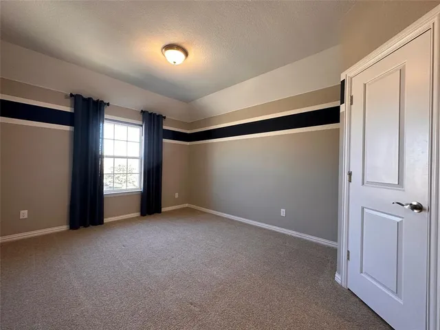 an empty room with a chandelier fan and windows