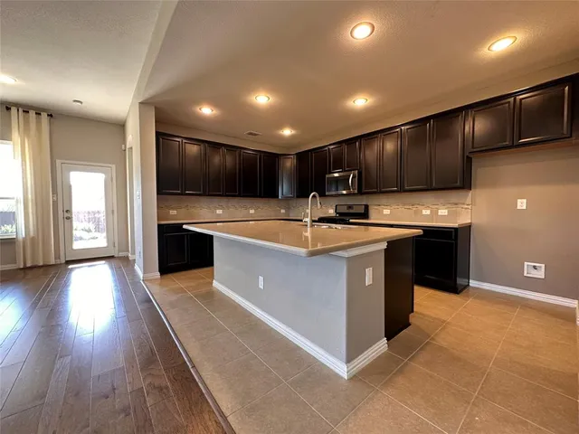 a kitchen with kitchen island granite countertop wooden cabinets and white stainless steel appliances