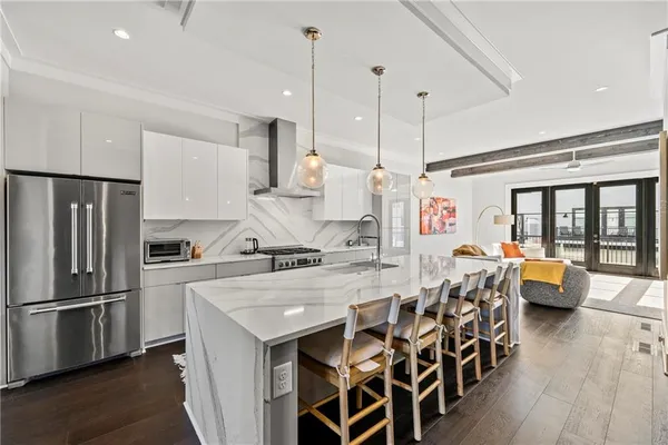 a kitchen with stainless steel appliances kitchen island granite countertop a table chairs and a refrigerator