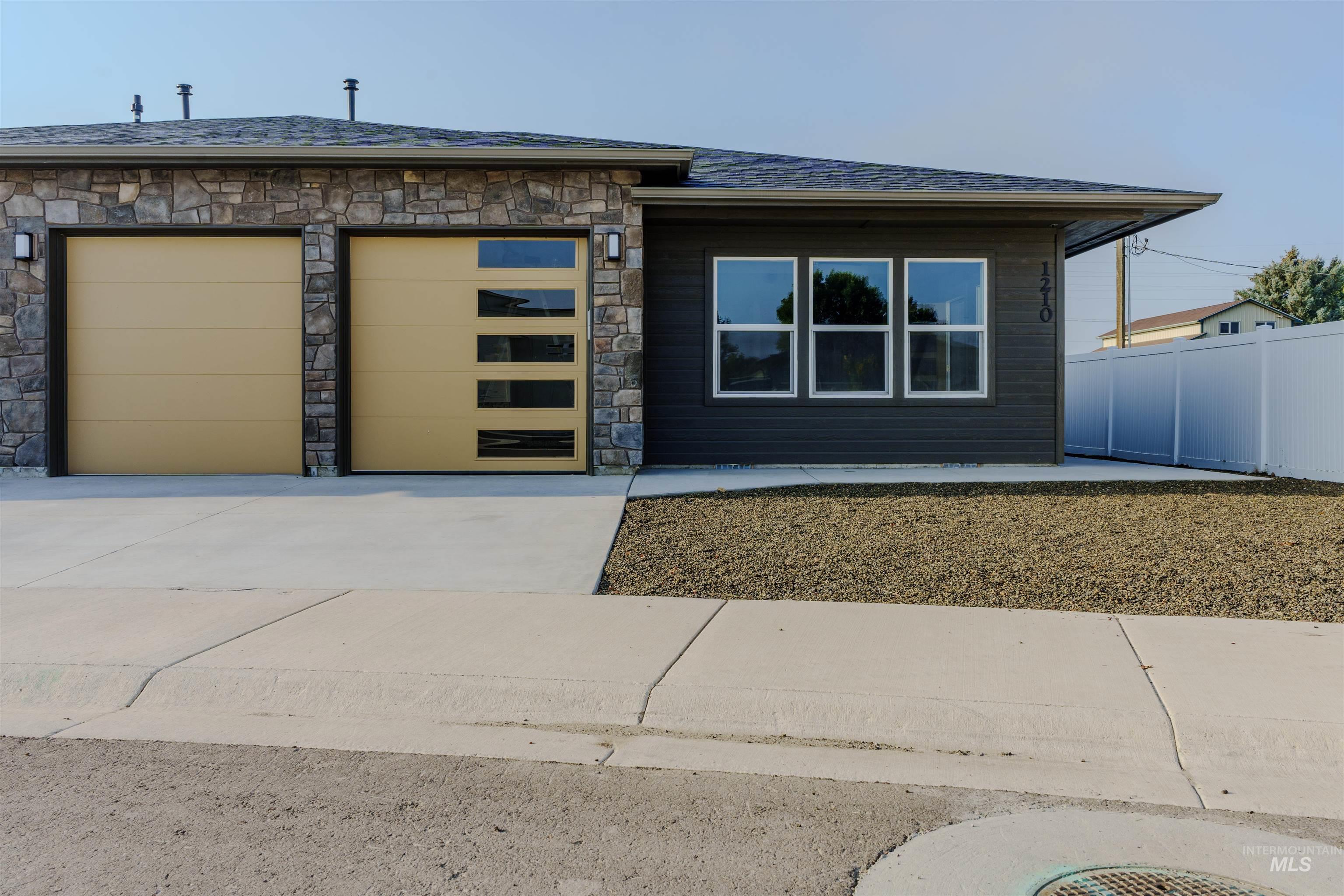 View of front of property with stone siding, concrete driveway, an attached garage, and roof with shingles