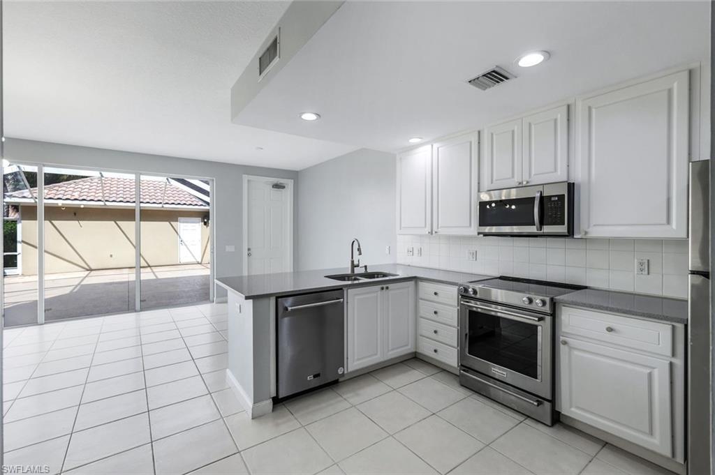 3462 Bravada Way Naples, FL 34119 - Photo 11 of 35 a kitchen with stainless steel appliances granite countertop a stove a sink and a microwave