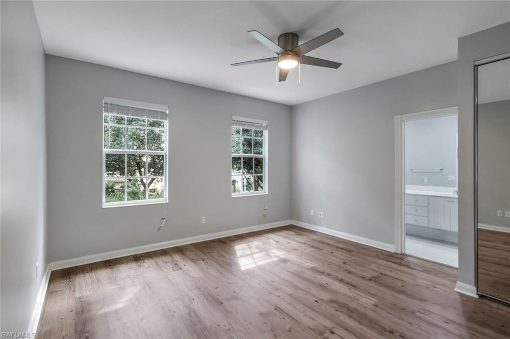3462 Bravada Way Naples, FL 34119 - Photo 15 of 35 an empty room with wooden floor chandelier fan and windows