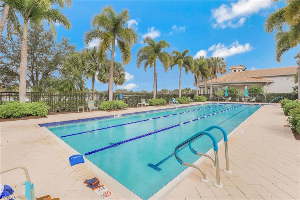 3462 Bravada Way Naples, FL 34119 - Photo 28 of 35 a view of a swimming pool with a lawn chairs under palm trees