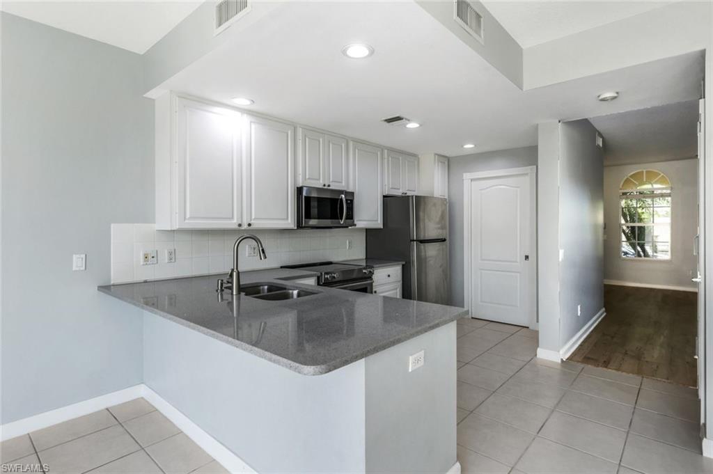3462 Bravada Way Naples, FL 34119 - Photo 10 of 35 a kitchen with stainless steel appliances granite countertop a refrigerator sink and stove