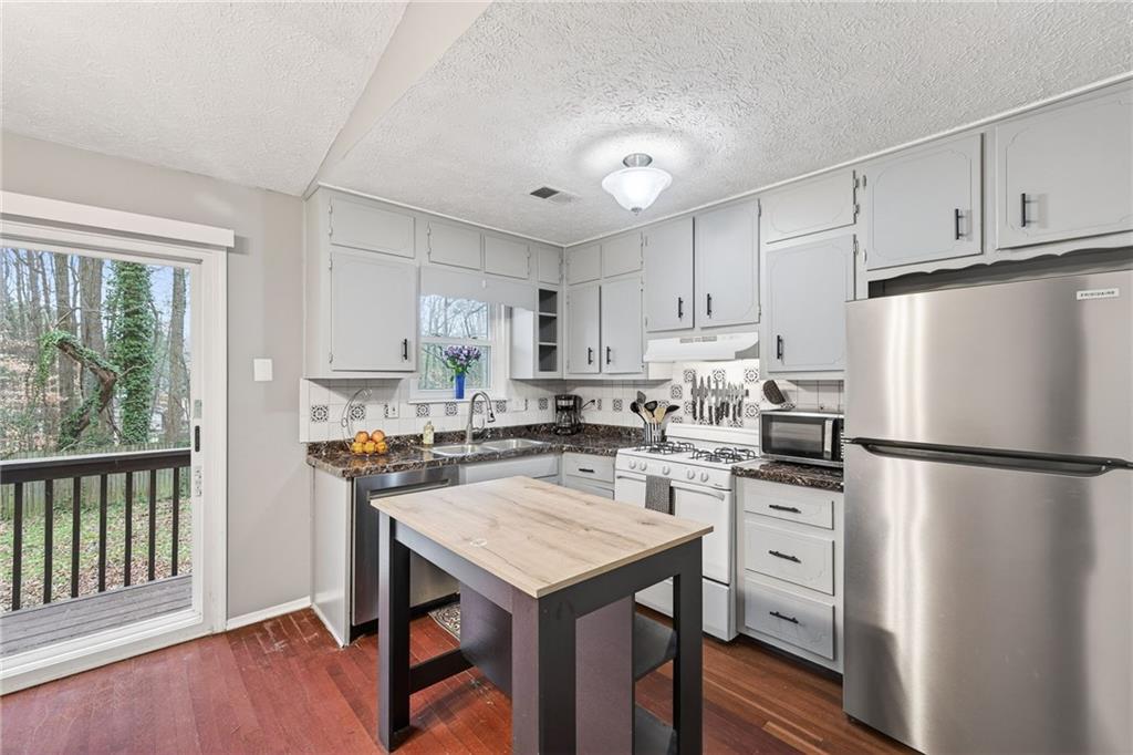 1572 Kings Ridge Drive Northwest Norcross, GA 30093 - Photo 6 of 20 a kitchen with a refrigerator a stove a sink and a microwave with wooden floor