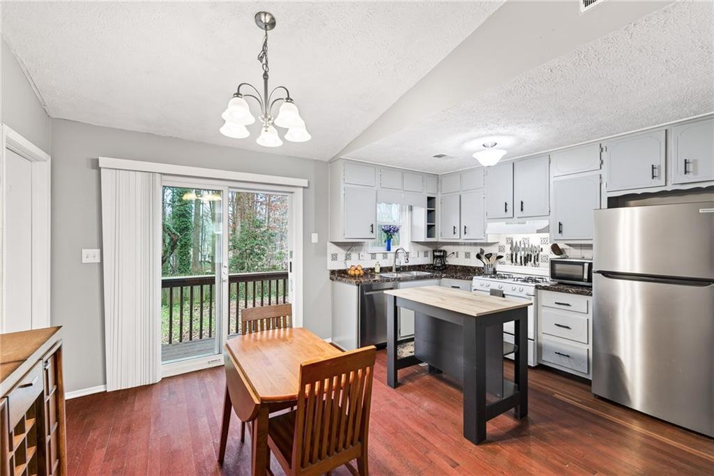1572 Kings Ridge Drive Northwest Norcross, GA 30093 - Photo 7 of 20 a kitchen with stainless steel appliances granite countertop a stove a refrigerator a sink dishwasher a dining table and chairs with wooden floor