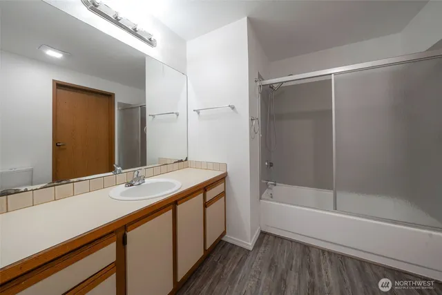 a bathroom with a tub shower vanity and a sink