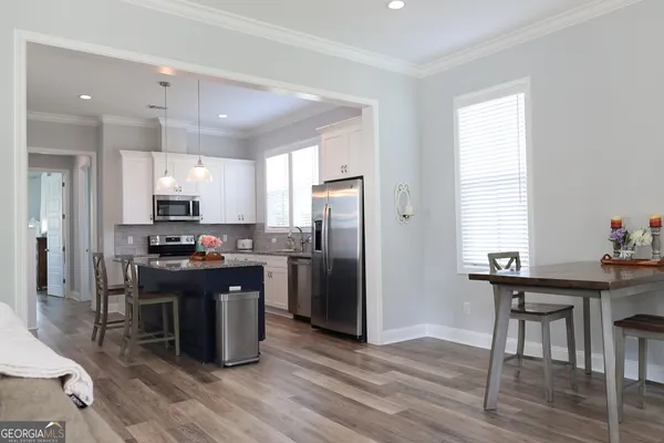 a kitchen with stainless steel appliances kitchen island granite countertop a table chairs refrigerator and sink