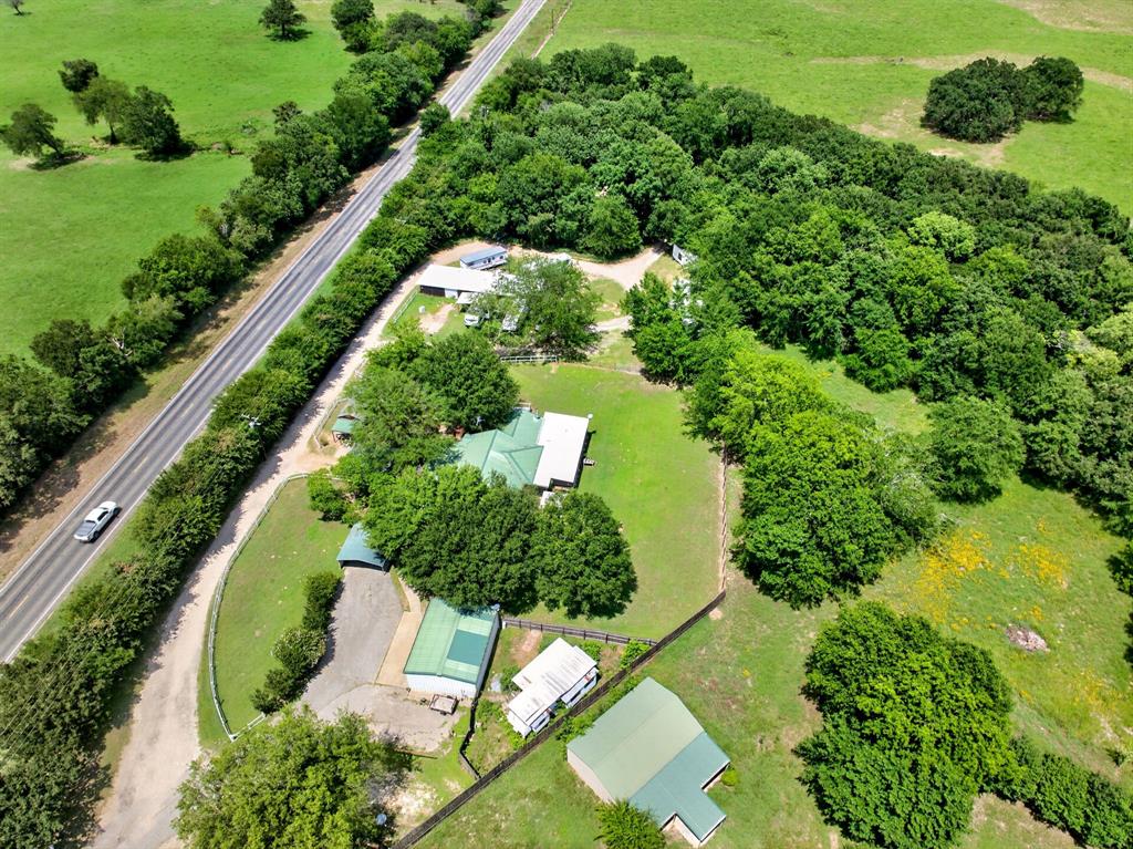 111 County Road 2806 Mabank, TX 75147 - Photo 30 of 34 Expansive rural property featuring a main residence with a green roof, multiple outbuildings, mature trees, and perimeter fencing