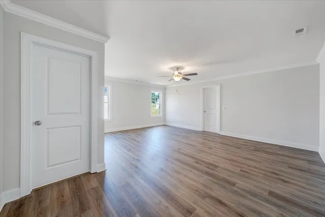 a view of an empty room with wooden floor and window