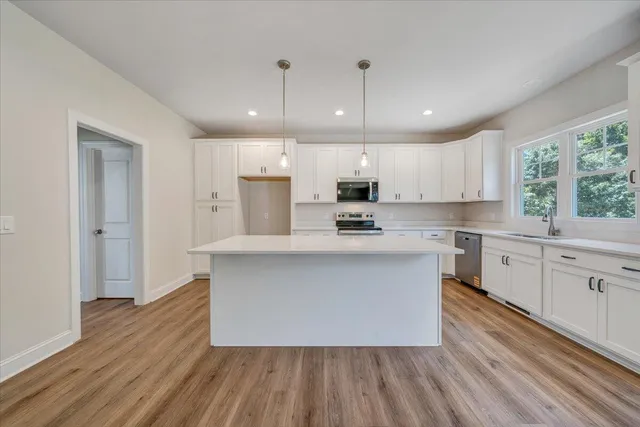 a large kitchen with stainless steel appliances a large center island attached withe living room