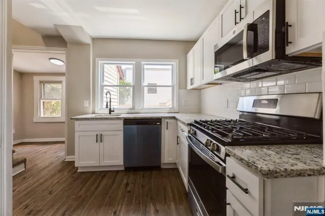 a kitchen with stainless steel appliances granite countertop a stove a sink and a microwave