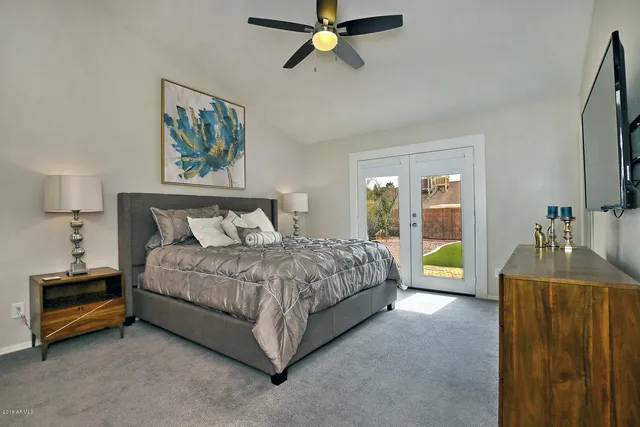 a spacious bedroom with a bed dresser and a flat tv screen