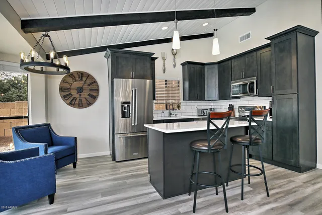 a kitchen with stainless steel appliances granite countertop a refrigerator a sink dishwasher a dining table and chairs with wooden floor