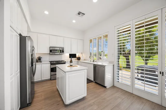 a kitchen with a refrigerator a stove top oven and white cabinets