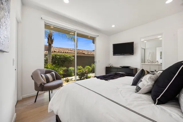 a bedroom with a bed a couch and a flat screen tv