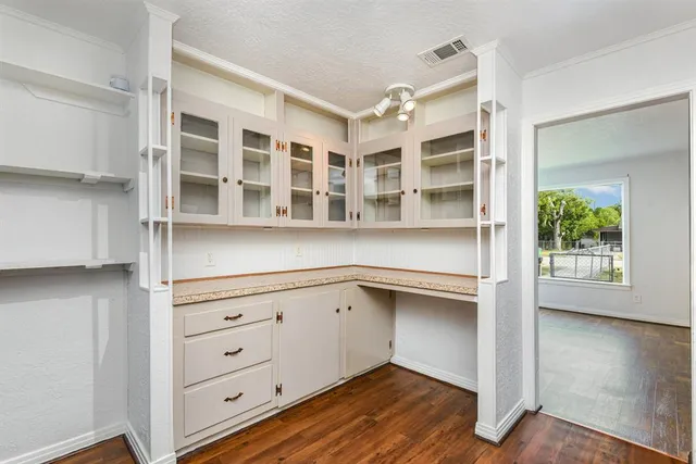 a view of an empty room with a cabinet and wooden floor