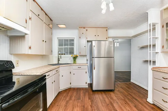 a kitchen with a refrigerator a sink and dishwasher a stove top oven with wooden floor