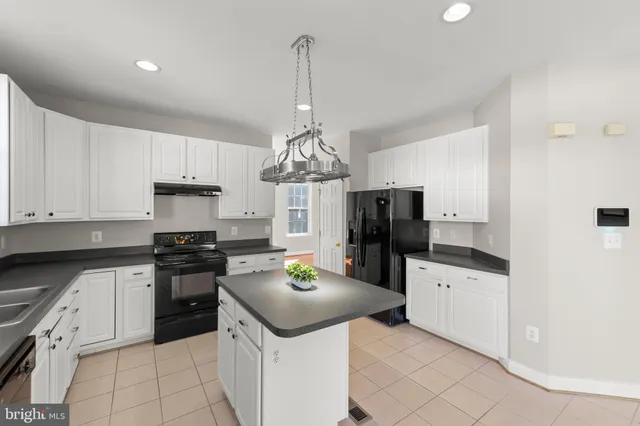 a kitchen with a stove a sink a center island and cabinets