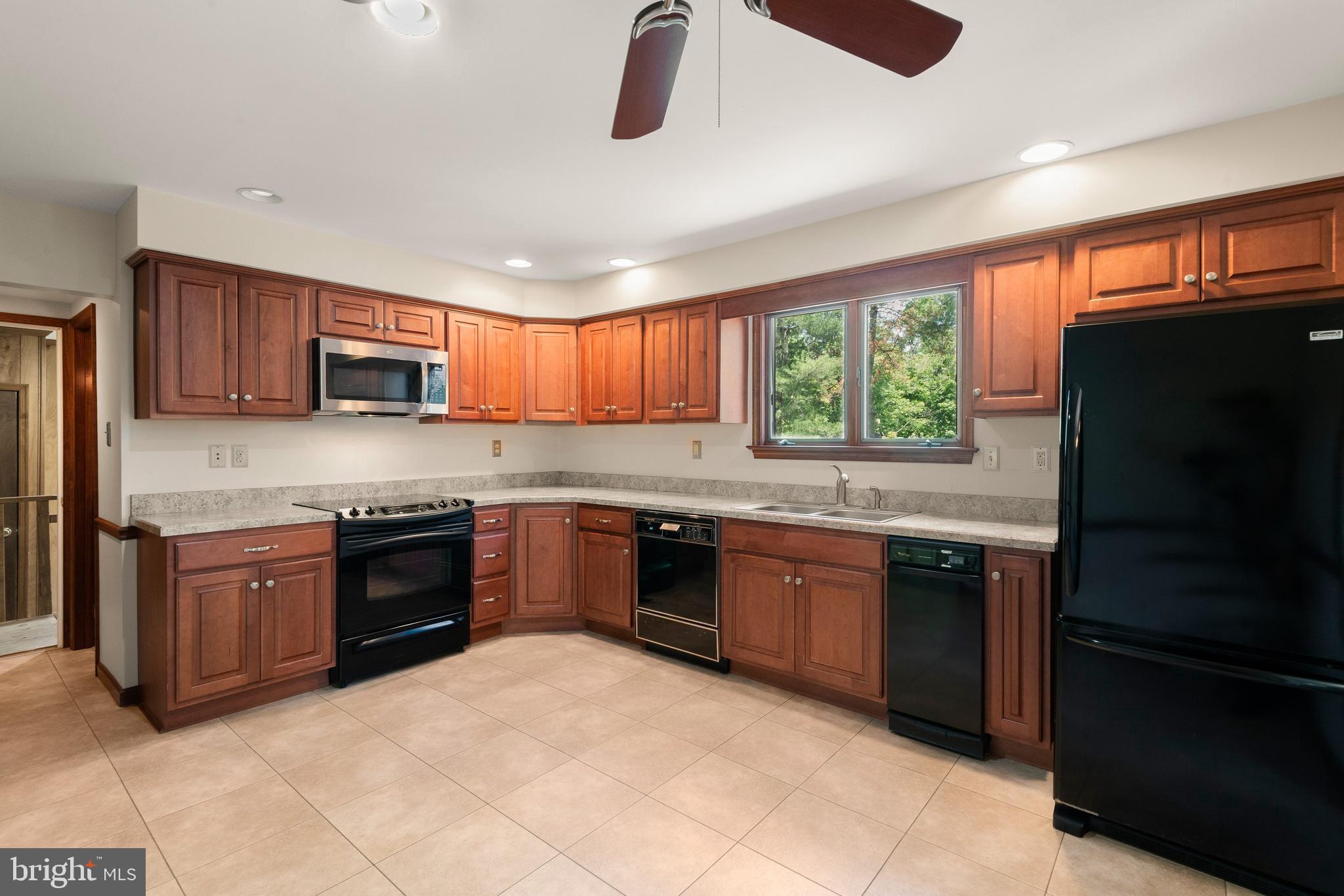 108 Sheeder Road Phoenixville, PA 19460 - Photo 10 of 42 a kitchen with stainless steel appliances granite countertop wooden cabinets a stove top oven a granite counter top and a window