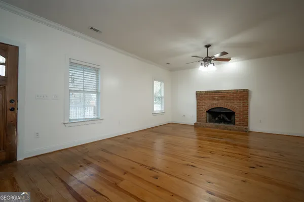 a view of an empty room with wooden floor fireplace and a window