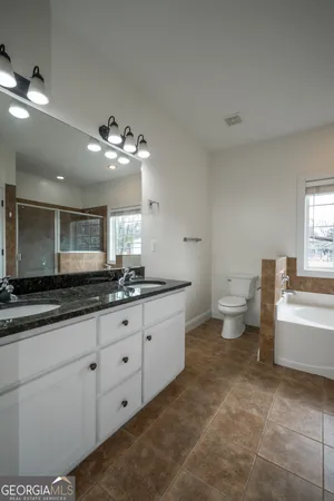 a bathroom with a granite countertop sink a toilet a mirror and bathtub