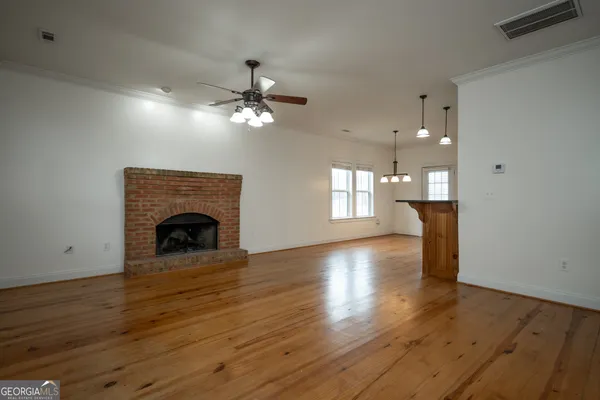 a view of an empty room with a fireplace and wooden floor