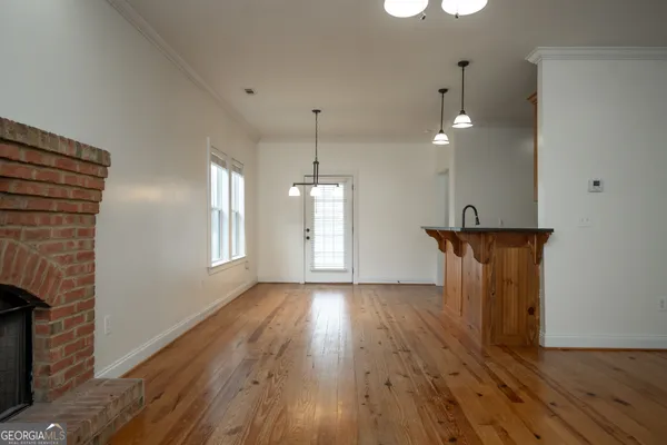an empty room with wooden floor fireplace and windows