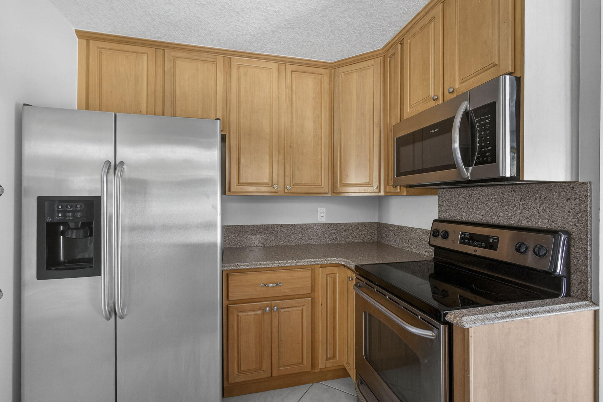 7107 181st Street Jupiter, FL 33458 - Photo 14 of 54 a kitchen with stainless steel appliances granite countertop a refrigerator a microwave a sink and cabinets