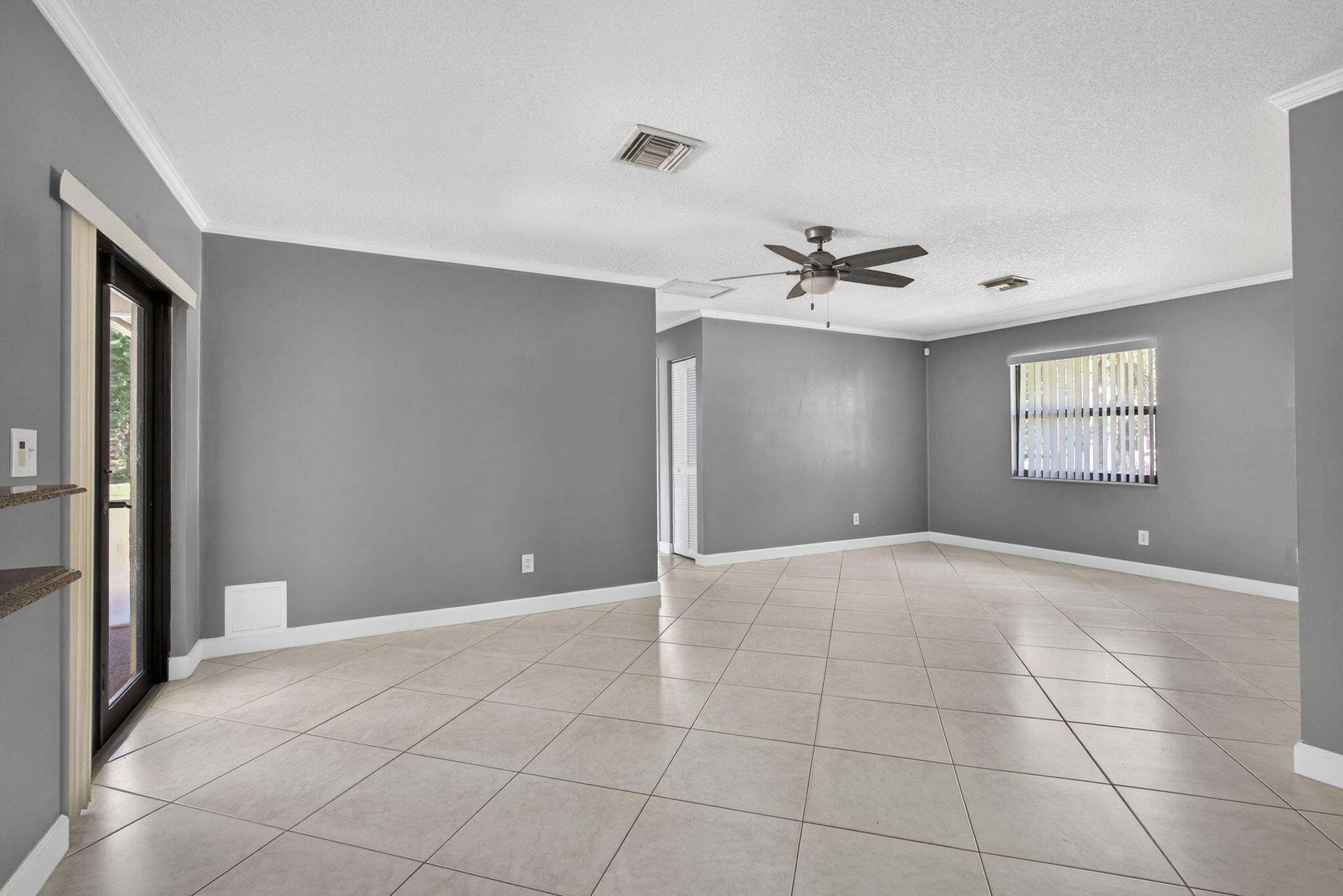 7107 181st Street Jupiter, FL 33458 - Photo 24 of 54 a view of an empty room with a ceiling fan and windows