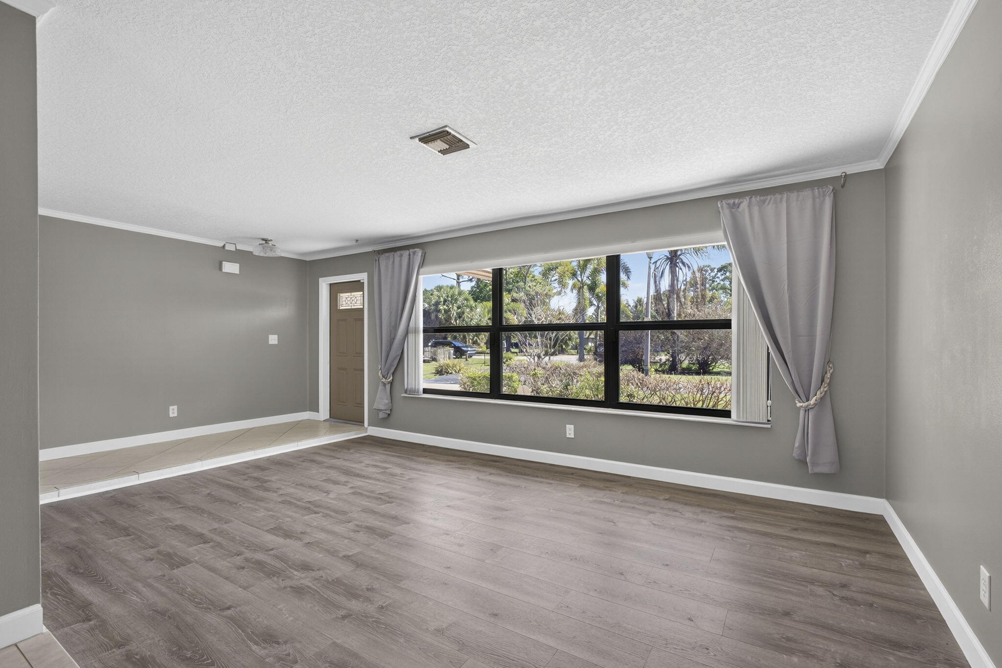 7107 181st Street Jupiter, FL 33458 - Photo 6 of 54 a view of an empty room with a window and wooden floor