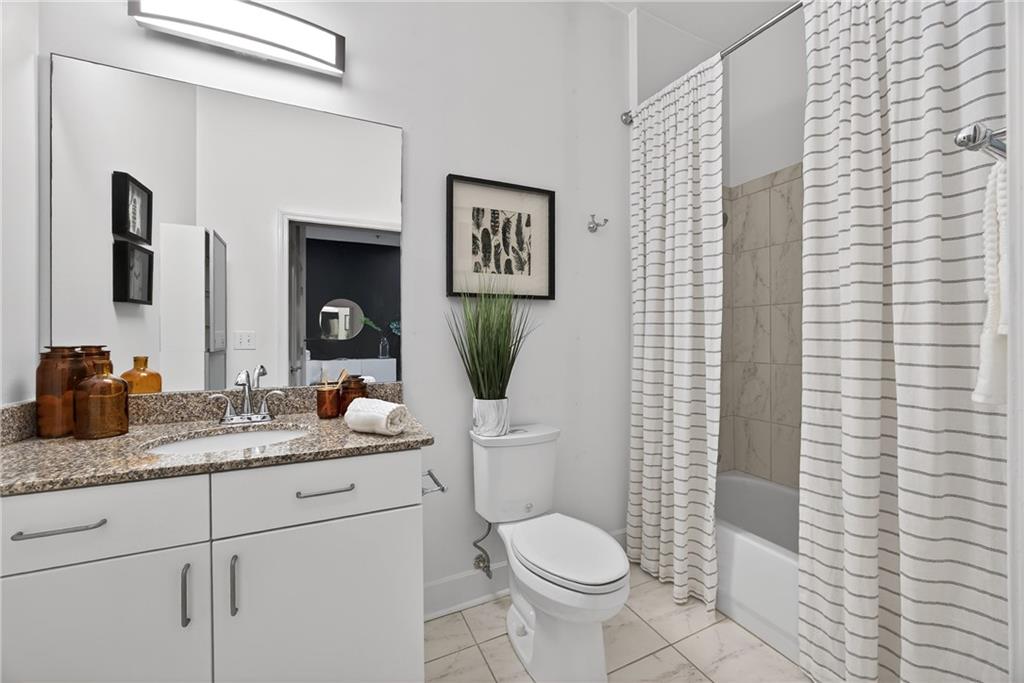 384 Ralph McGill Boulevard Northeast, Unit 322 Atlanta, GA 30312 - Photo 19 of 23 a bathroom with a granite countertop toilet sink and mirror
