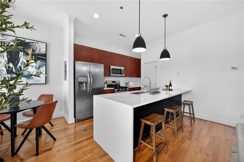 384 Ralph McGill Boulevard Northeast, Unit 322 Atlanta, GA 30312 - Photo 5 of 23 a kitchen with stainless steel appliances kitchen island granite countertop a sink a refrigerator and a wooden floor