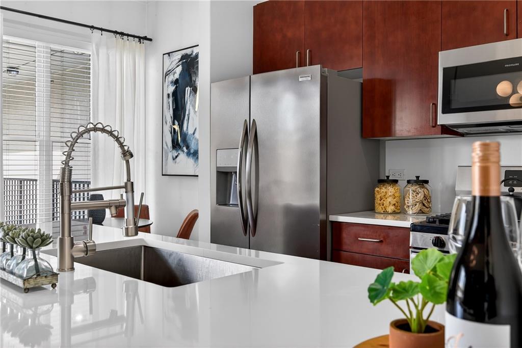 384 Ralph McGill Boulevard Northeast, Unit 322 Atlanta, GA 30312 - Photo 9 of 23 a kitchen with stainless steel appliances a refrigerator a sink a stove a microwave a dining table and chairs
