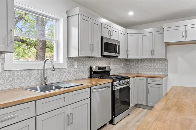 a kitchen with stainless steel appliances granite countertop white cabinets a window and a sink