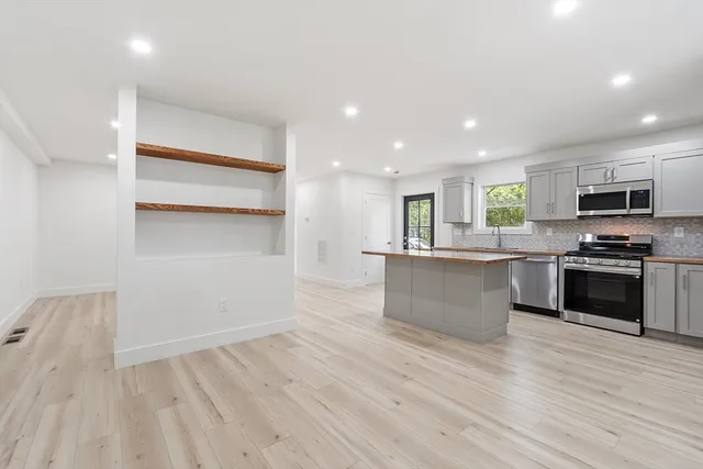 a large kitchen with granite countertop a large counter top stainless steel appliances and cabinets