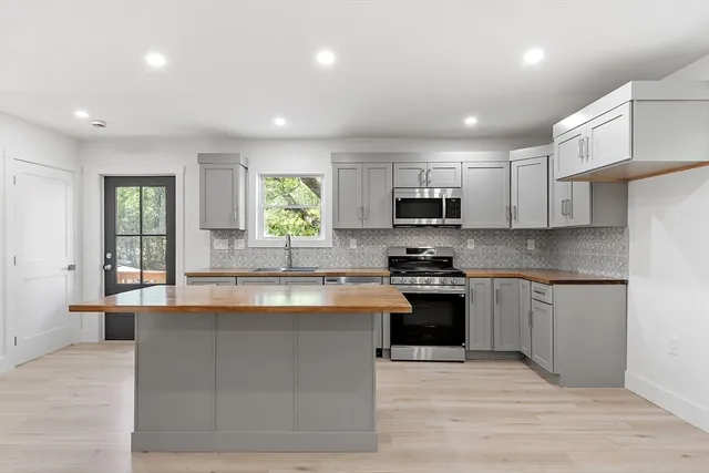 a large kitchen with granite countertop a stove top oven a sink dishwasher a dining table and chairs with wooden floor