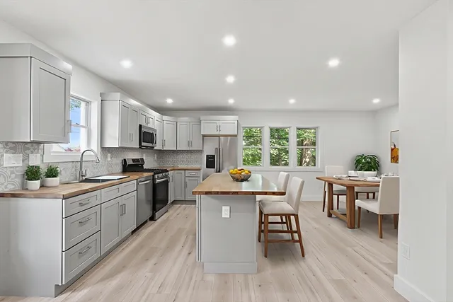 a kitchen with stainless steel appliances granite countertop wooden cabinets a center island and a window