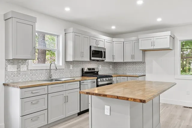 a kitchen with granite countertop a sink and a stove top oven with white cabinets