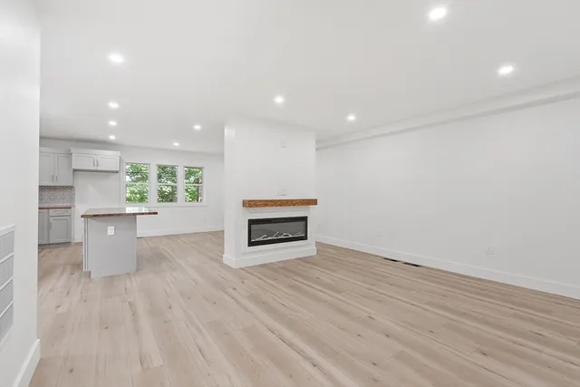 a view of kitchen and empty room with wooden floor and windows