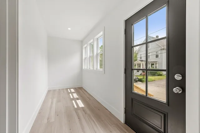 a view of hallway with window and wooden floor