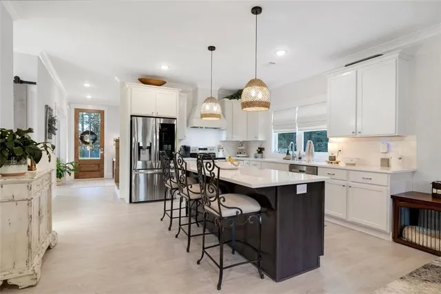 a open kitchen with stainless steel appliances granite countertop a stove a sink a oven a dining table and chairs with wooden floor