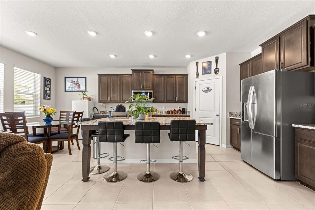 8142 Southwest 59th Avenue Ocala, FL 34476 - Photo 14 of 54 a kitchen with stainless steel appliances kitchen island granite countertop a refrigerator a stove a sink a dining table and chairs