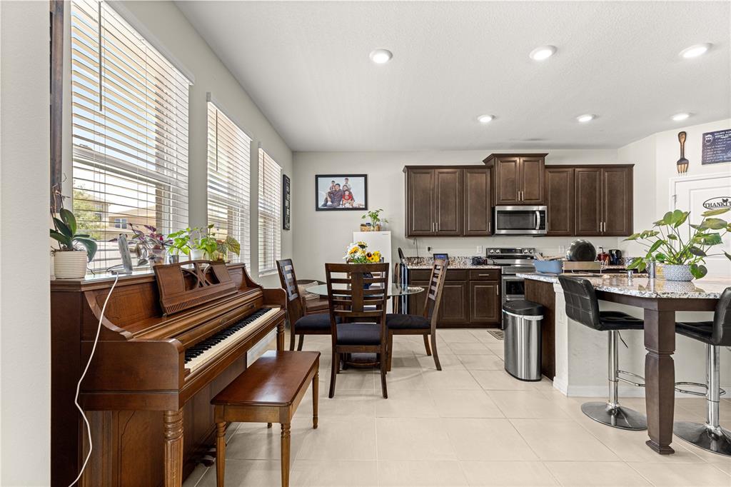8142 Southwest 59th Avenue Ocala, FL 34476 - Photo 15 of 54 a kitchen with stainless steel appliances kitchen island granite countertop a refrigerator a stove a sink a dining table and chairs