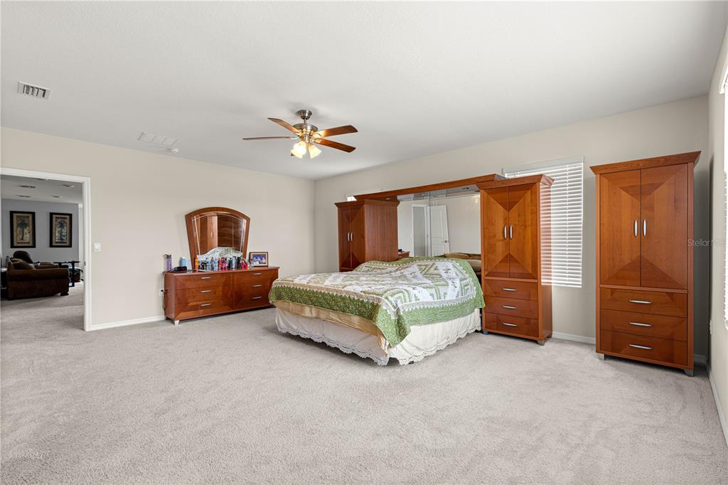 8142 Southwest 59th Avenue Ocala, FL 34476 - Photo 23 of 54 a spacious bedroom with a bed and a chandelier