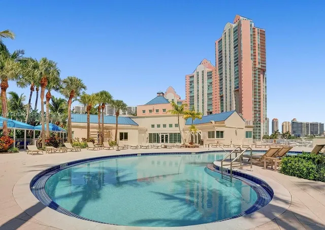 a view of a swimming pool with a lawn chairs and palm tree